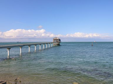 A long pier extending over the sea with a building at the end and several ships in the water at 117 Crosswinds in Hillway near Bembridge