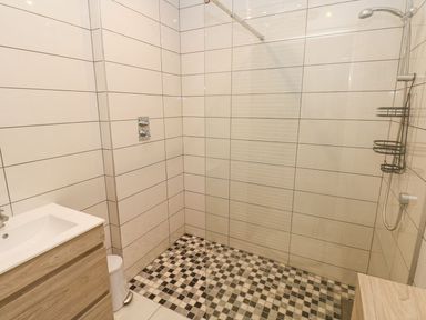 A bathroom with a shower area featuring a glass partition and checkered floor tiles at Golygfa Hafan in Little Haven