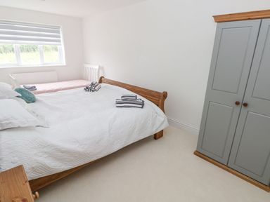 A bedroom with two beds and a gray wardrobe at Golygfa Hafan in Little Haven