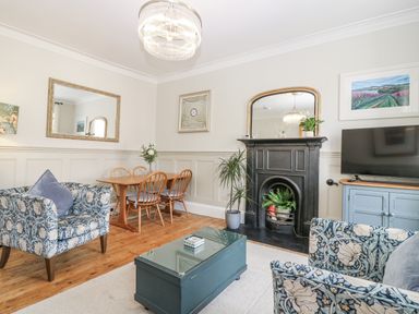 A living room with a fireplace and dining area at 11A High Street in Jedburgh