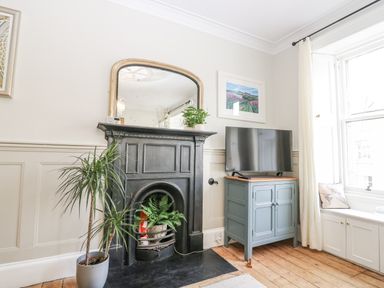 A living room with a fireplace and television at 11A High Street in Jedburgh