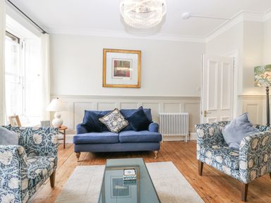 A living room with a blue sofa and patterned armchairs at 11A High Street in Jedburgh