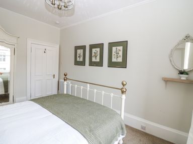 A bedroom with a bed, paintings on the wall and a mirror at 11A High Street in Jedburgh