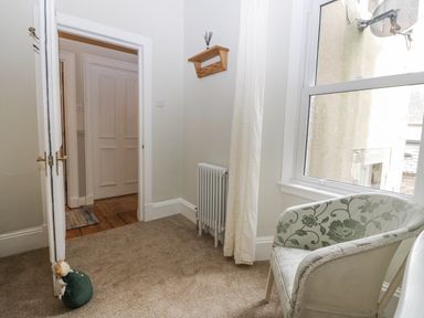 A hallway with a chair and radiator at 11A High Street, Jedburgh