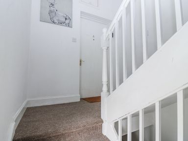A staircase and front door in a hallway at 11A High Street Jedburgh