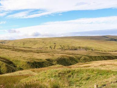 A grassy hilly landscape with a partly cloudy blue sky at The Museum in Nenthead