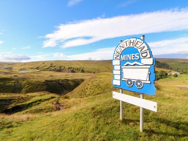 A landscape with grassy hills and a sign reading Nenthead Mines at The Museum in Nenthead