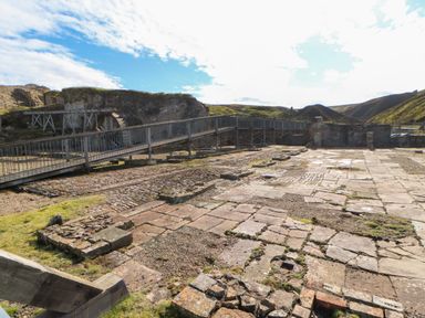 An outdoor area with stone ruins and a metal walkway with hills in the background at The Museum in Nenthead
