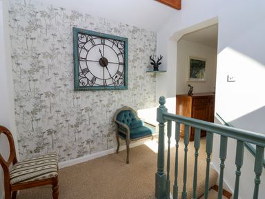 A hallway with a clock on the wall and a chair at The Museum in Nenthead