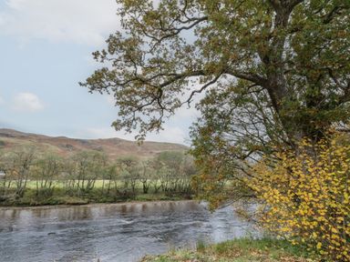 A river with trees on its banks and hills in the background at Bradan Lodge in Dalmally