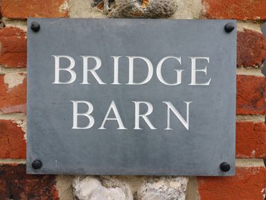 A stone wall with a mounted sign reading Bridge Barn at Bridge Barn in Sidestrand near Overstrand