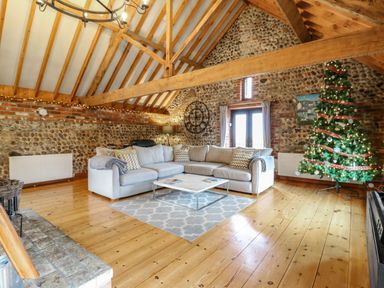 A living room with a sectional sofa coffee table and a decorated Christmas tree at Bridge Barn in Sidestrand near Overstrand
