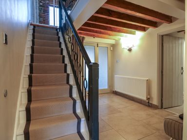 A hallway with carpeted stairs and exposed wooden ceiling beams at Bridge Barn in Sidestrand near Overstrand