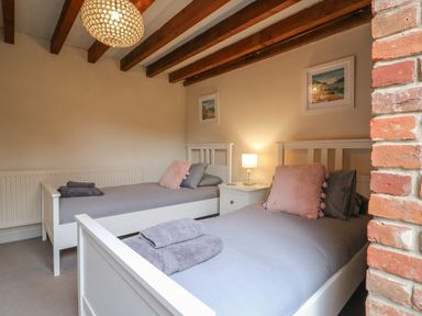 A bedroom with two single beds bedside table and lamp Bridge Barn Sidestrand near Overstrand