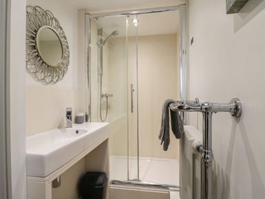 A bathroom with a sink mirror shower area and a towel on a radiator at Bridge Barn in Sidestrand near Overstrand