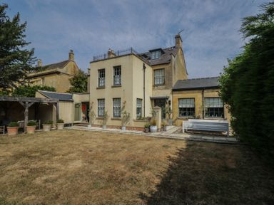 A garden with a house and planters at Cotswold House in Moreton-In-Marsh