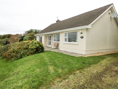 A single story house with a tiled roof and garden at Lakeview Lodge in Knockmore County Mayo
