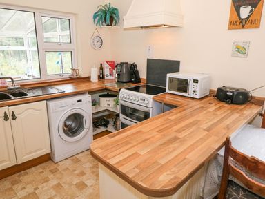 A kitchen with sink washing machine stove microwave wooden countertops and a small radio at Lakeview Lodge in Knockmore County Mayo