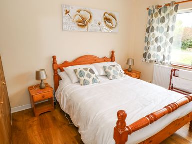 A bedroom with a wooden bed and matching nightstands with lamps at Lakeview Lodge in Knockmore County Mayo