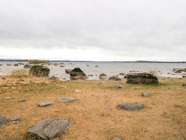 A rocky shoreline with scattered stones and a body of water under a cloudy sky at Lakeview Lodge in Knockmore County Mayo