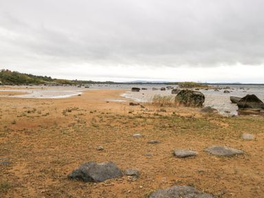 A sandy beach with scattered rocks and water under a cloudy sky at Lakeview Lodge in Knockmore County Mayo