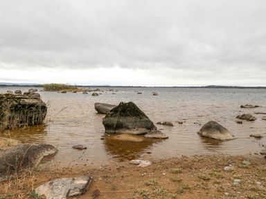 A lakeshore with rocks in the water under a cloudy sky at Lakeview Lodge in Knockmore County Mayo
