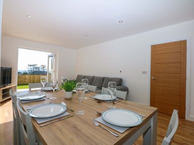 A dining room with a table set for dinner at 15 Llys Tegeirian Llangristiolus near Llangefni
