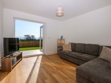 A living room with a sofa and television at 15 Llys Tegeirian in Llangristiolus near Llangefni