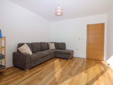 A living room with a sofa and shelf at 15 Llys Tegeirian Llangristiolus near Llangefni