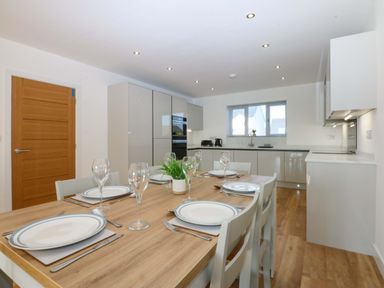 A kitchen with dining table and chairs at 15 Llys Tegeirian in Llangristiolus near Llangefni
