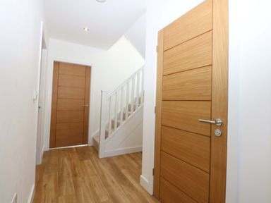 A hallway with doors and a staircase at 15 Llys Tegeirian in Llangristiolus near Llangefni
