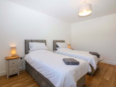 A bedroom with twin beds and a bedside table at 15 Llys Tegeirian in Llangristiolus near Llangefni
