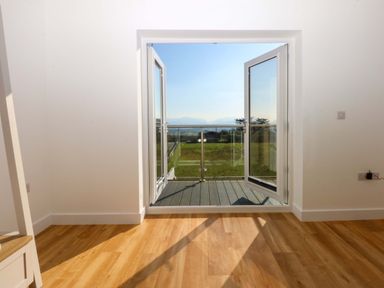 A room with open doors leading to a balcony at 15 Llys Tegeirian, Llangristiolus near Llangefni