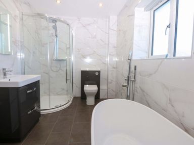 A bathroom with a shower, bathtub, and sink at 15 Llys Tegeirian in Llangristiolus near Llangefni