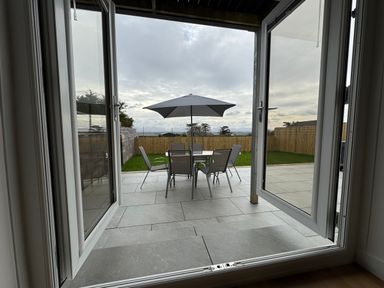 An outdoor area with a table and chairs under an umbrella at Golygfa in Llangristiolus near Llangefni