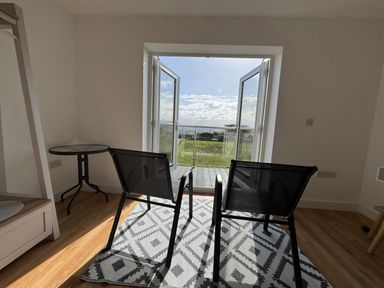 A room with chairs and a table overlooking a landscape at Golygfa in Llangristiolus near Llangefni