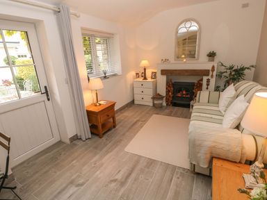 A living room with a striped sofa pillows a fireplace wooden furniture and lamps at Little Cloud Nash near Cowbridge