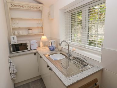 A small kitchen with a sink dish rack and window blinds at Little Cloud Nash near Cowbridge