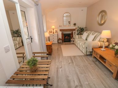 A living room with a striped sofa fireplaces two lamps wooden tables and a small wooden dining set at Little Cloud in Nash near Cowbridge