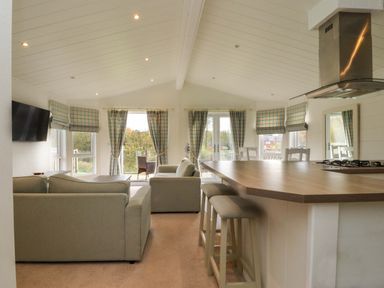 An open plan living and kitchen area with sofas and bar stools at Lakeview Lodge in Forton near Garstang