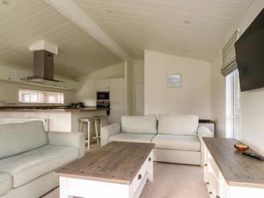 A living room with sofas coffee table and kitchen area with stools at Lakeview Lodge Forton near Garstang