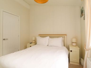 A bedroom with a double bed white bedding two side tables with lamps and a closed door at Lakeview Lodge in Forton near Garstang