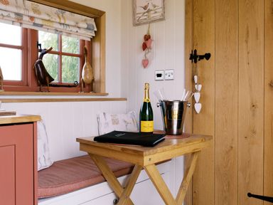 A corner with a table, champagne bottle, and decorative objects at Bonnie's Shepherds Hut at Shepherds Lodge Retreat and Wellness Bottesford near Redmile and Vale of Belvoir