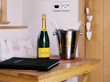A table with a champagne bottle and glasses at Bonnie's Shepherds Hut at Shepherds Lodge Retreat and Wellness Bottesford near Redmile and Vale of Belvoir