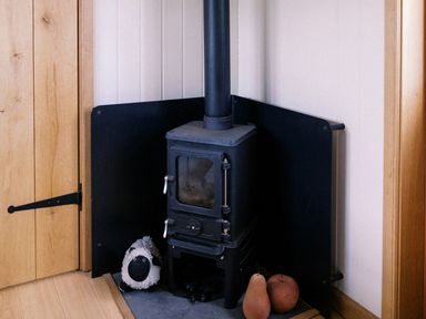 A wood stove with a black screen and a stuffed animal at Bonnie's Shepherds Hut at Shepherds Lodge Retreat and Wellness, Bottesford near Redmile and Vale of Belvoir
