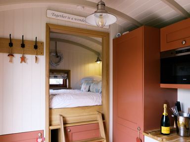 A kitchen with a bed area in a wooden hut at Bonnie's Shepherds Hut at Shepherds Lodge Retreat and Wellness Bottesford near Redmile and Vale of Belvoir