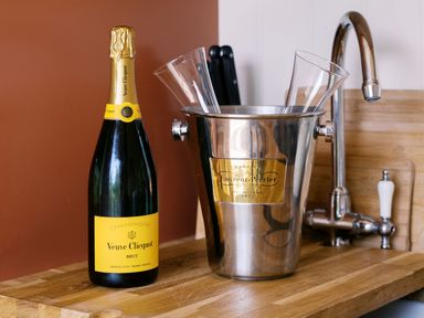 A champagne bottle and bucket with glasses beside a sink at Bonnie's Shepherds Hut at Shepherds Lodge Retreat and Wellness in Bottesford near Redmile and Vale of Belvoir