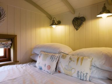 A bedroom with pillows and a window at Bonnie's Shepherds Hut at Shepherds Lodge Retreat and Wellness Bottesford near Redmile and Vale of Belvoir