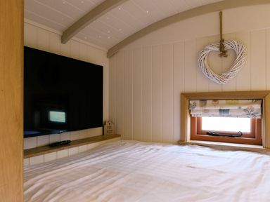 A bedroom with a television and window at Bonnie's Shepherds Hut at Shepherds Lodge Retreat and Wellness in Bottesford near Redmile and Vale of Belvoir