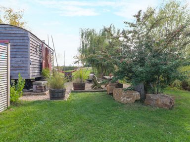 An outdoor area with a wooden wagon, planters, and seating at Bonnie's Shepherds Hut at Shepherds Lodge Retreat and Wellness Bottesford near Redmile and Vale of Belvoir